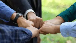 Hands coming together in a circle with a grass background