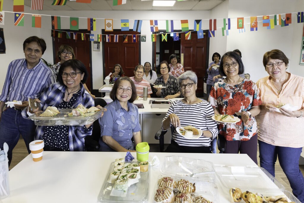 Digital skills learners enjoying a social lunch in the classroom, smiling and looking happy.